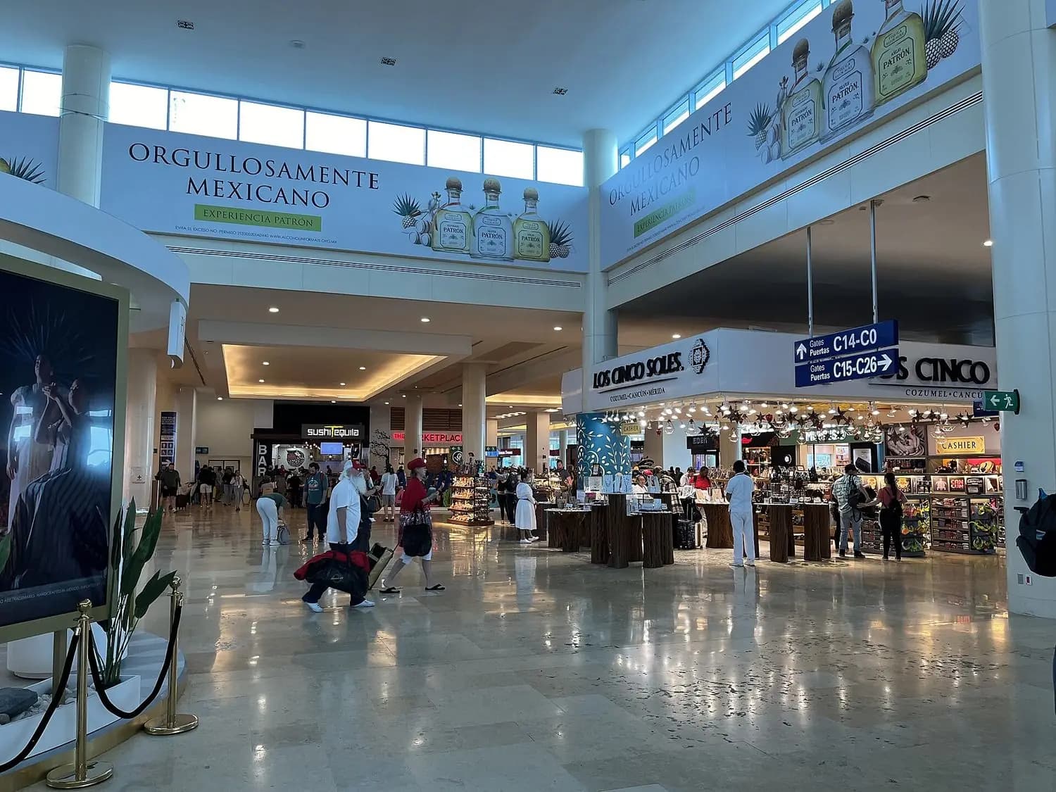 Vestíbulo de una terminal del Aeropuerto Internacional de Cancún, con tiendas y pasajeros