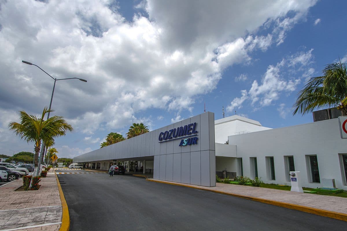 Acceso al Aeropuerto Internacional de Cozumel, con palmeras a los lados