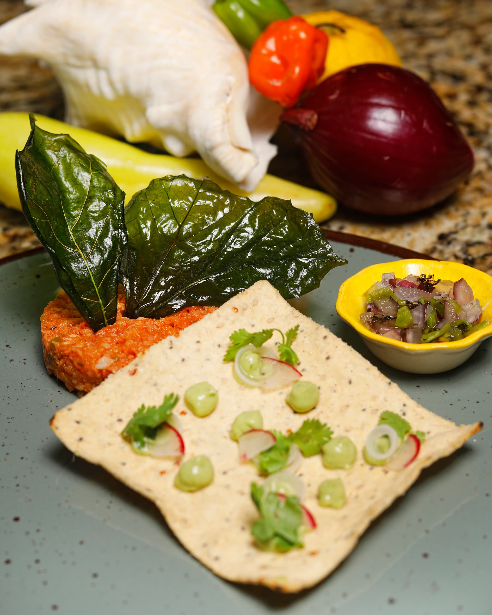 Tostada de caracol con aguacate y rábano, junto a chiles y cebolla