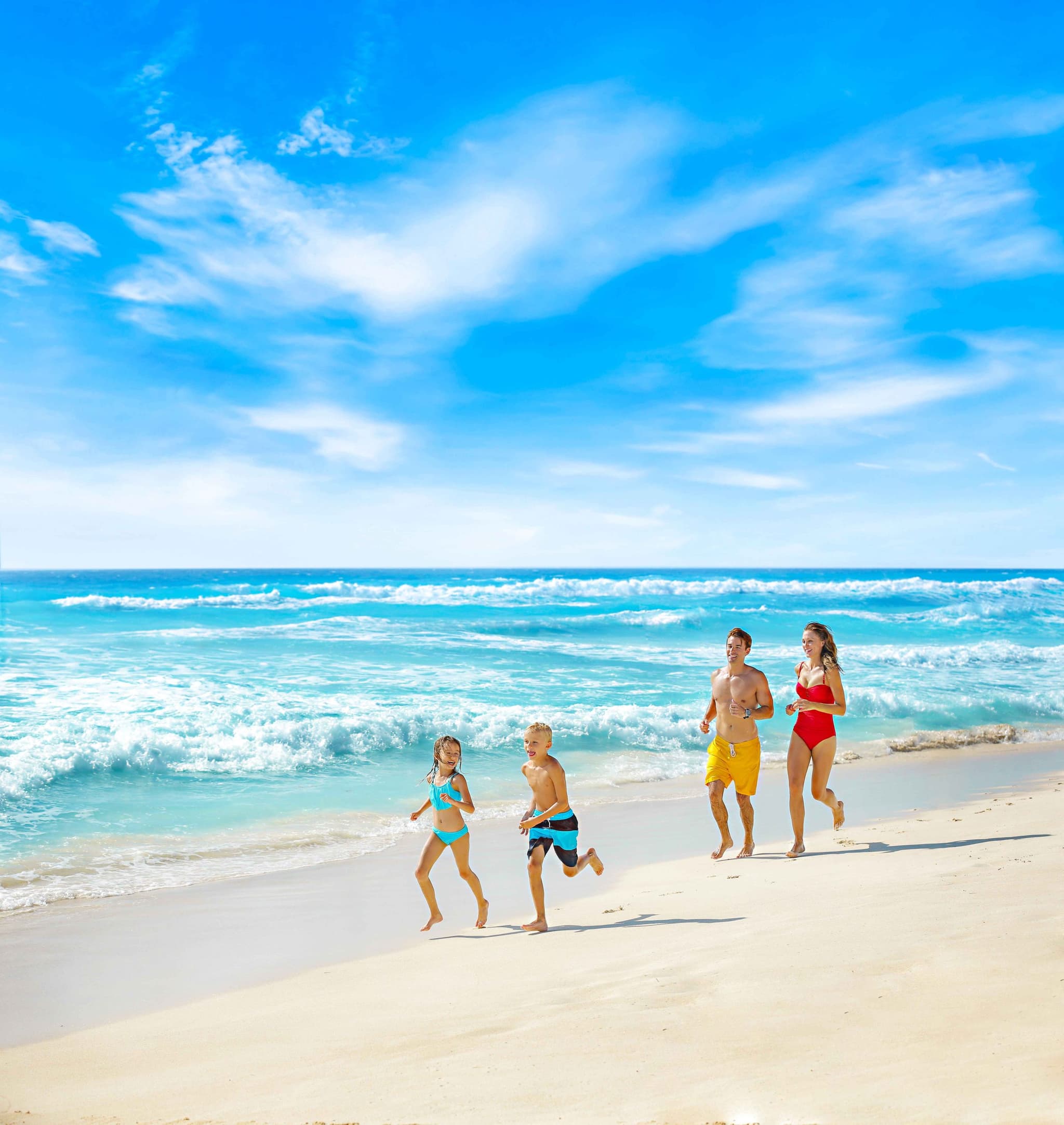 Familia corriendo por la orilla en una playa de arena blanca