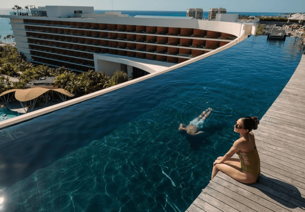 Alberca infinita frente al mar con el edificio del resort detrás
