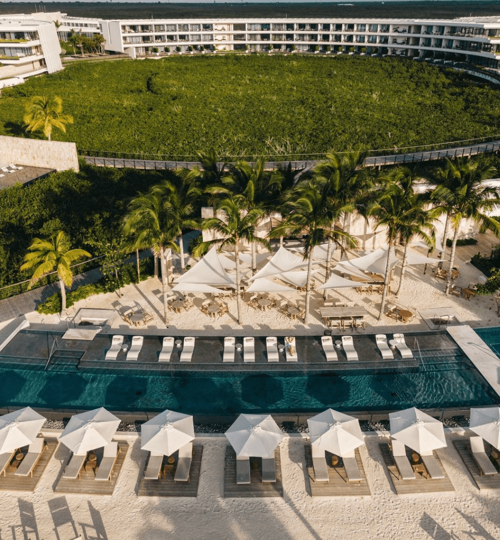 Vista aérea de la alberca, las sombrillas y el edificio curvo del resort