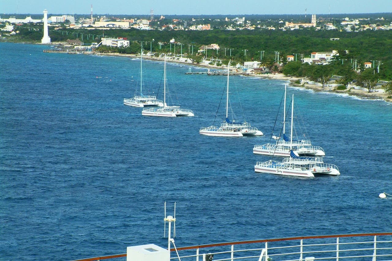 Costa de Cozumel vista desde el mar, con catamaranes fondeados frente a San Miguel