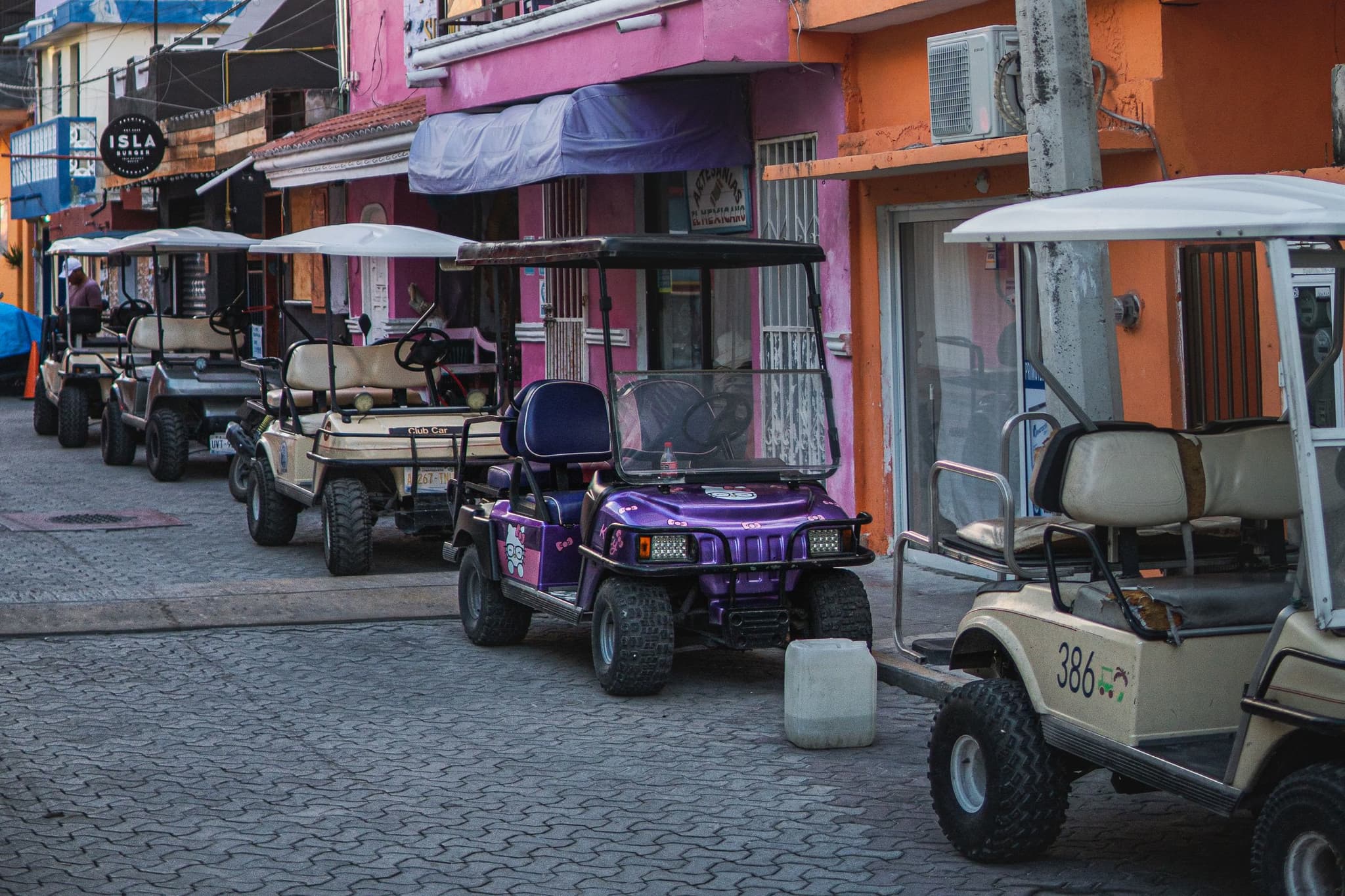 Carritos de golf estacionados en una calle empedrada del centro de Isla Mujeres