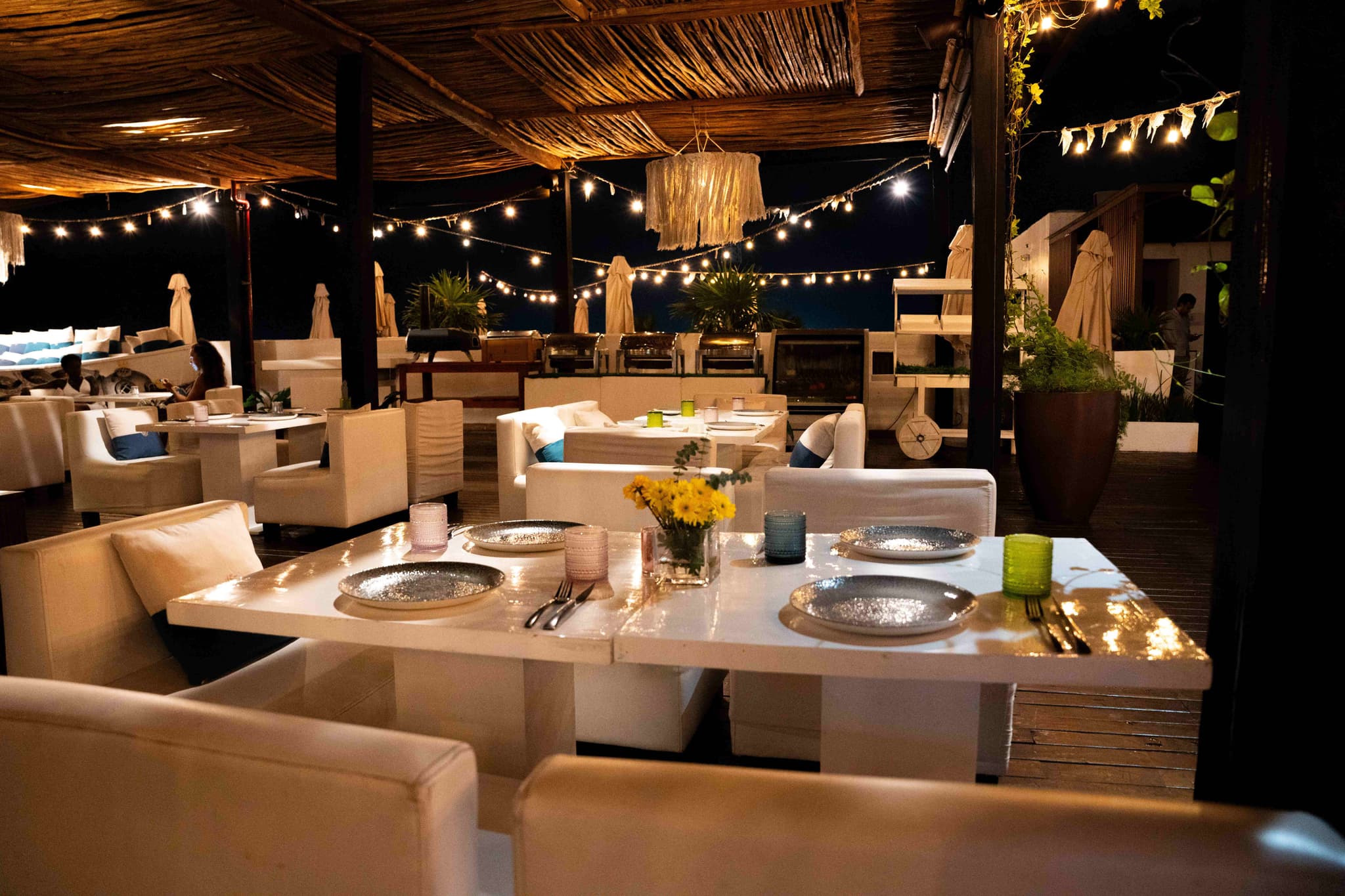 Mesa puesta en un restaurante de playa bajo guirnaldas de luces