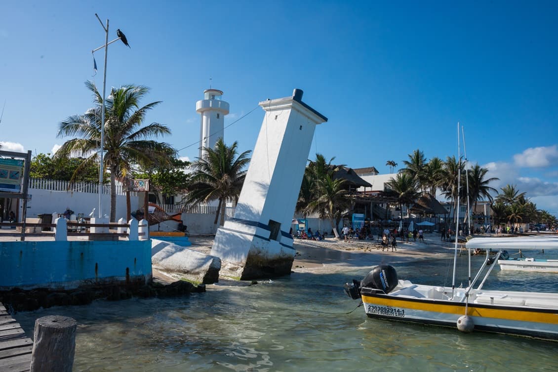Faro inclinado y embarcaciones en el muelle de Puerto Morelos