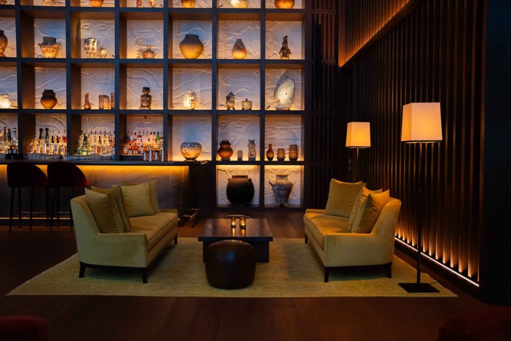 Bar de hotel con vitrinas iluminadas y sillones de terciopelo