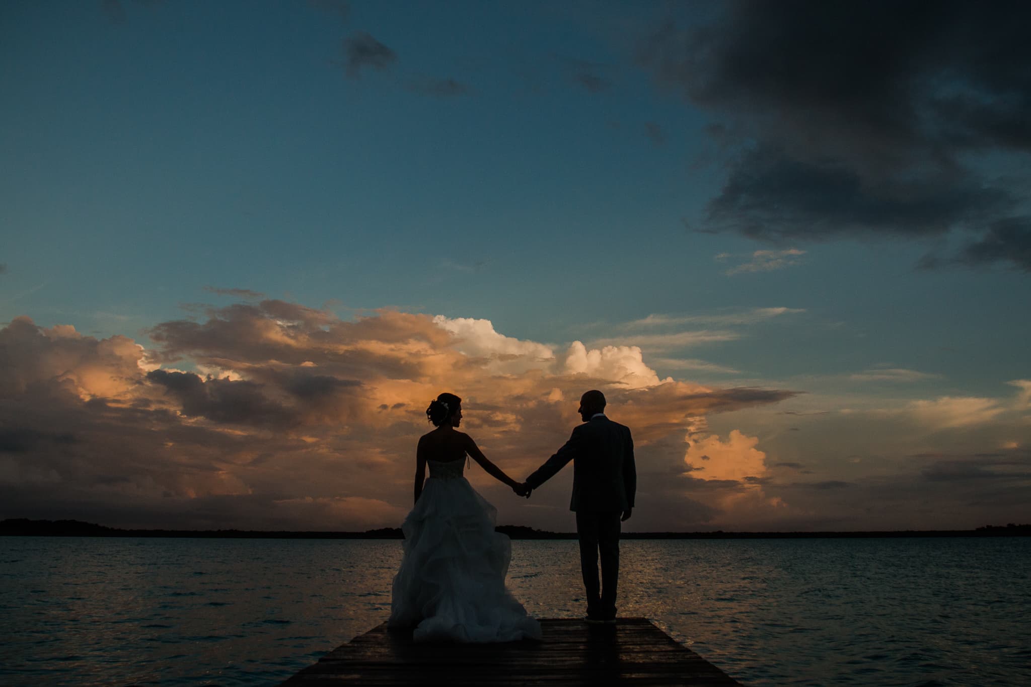 Novios en un muelle sobre la laguna de Bacalar al anochecer