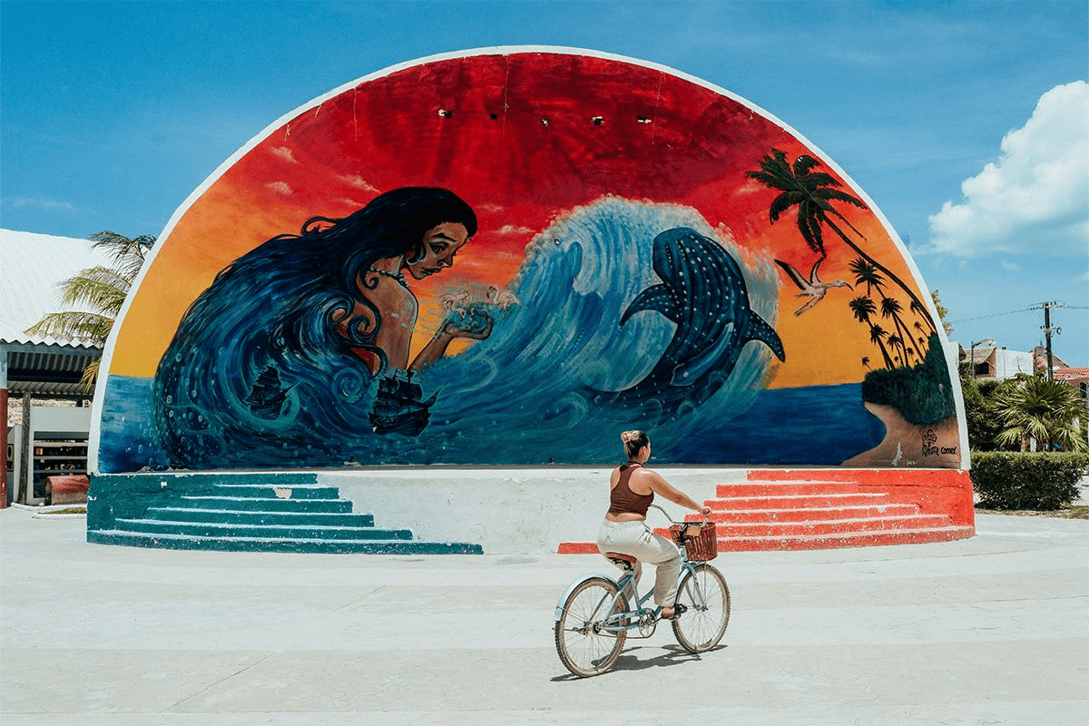 Ciclista frente a un mural de tiburón ballena en Holbox