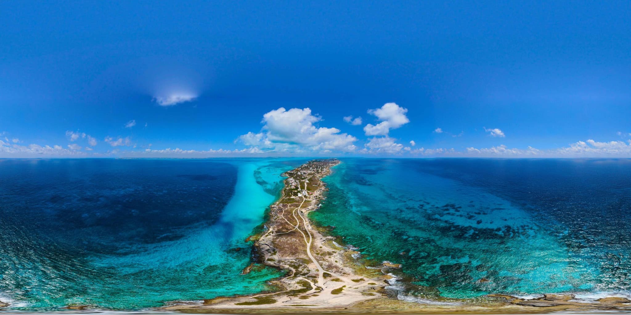 Vista aérea de Isla Mujeres entre el azul profundo del mar y el agua turquesa de la orilla