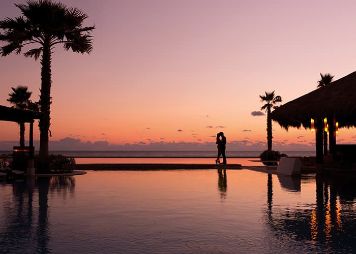 Pareja abrazada al atardecer junto a una alberca frente al Caribe
