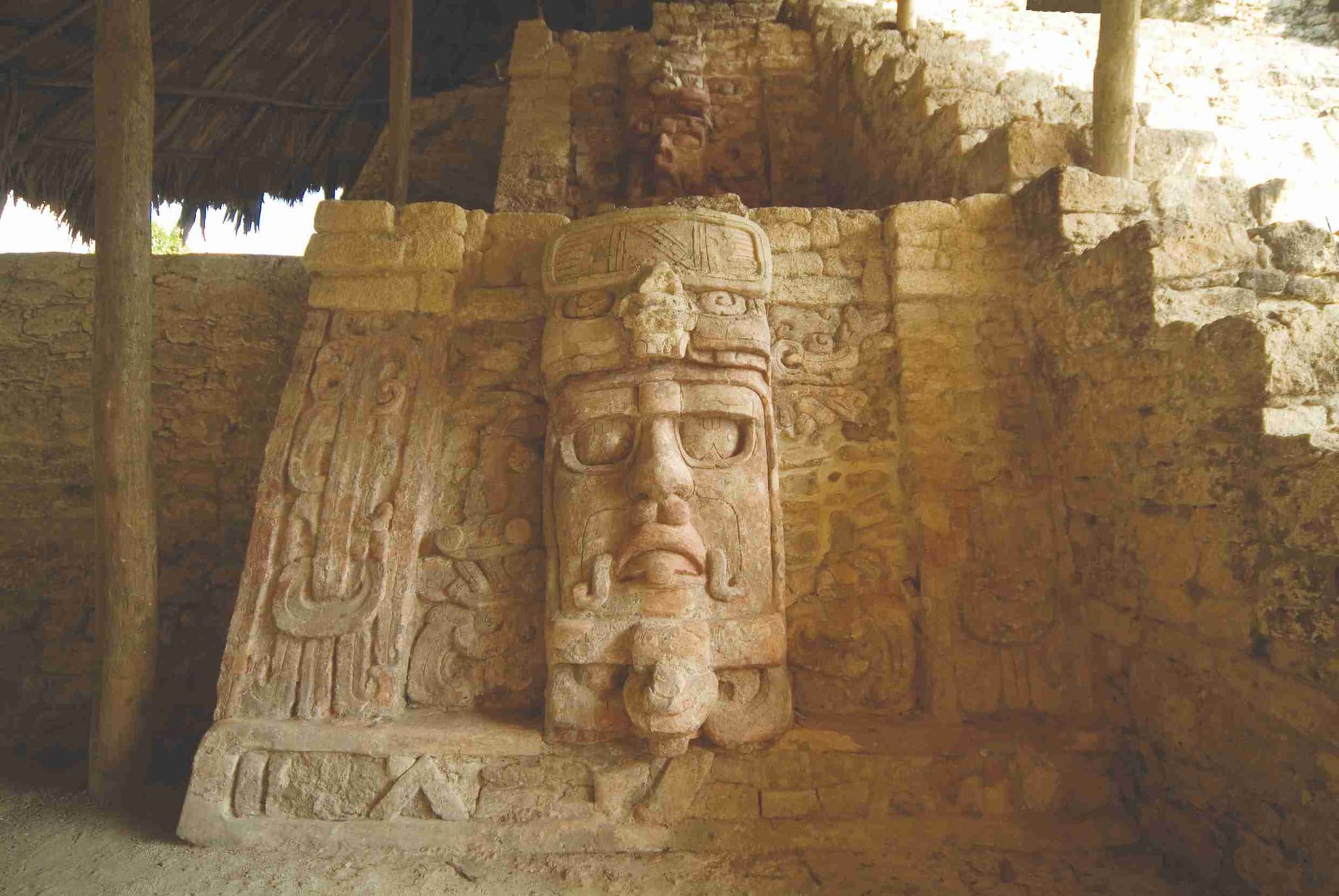Mascarón de estuco del dios sol en Kohunlich, bajo su techo de palma