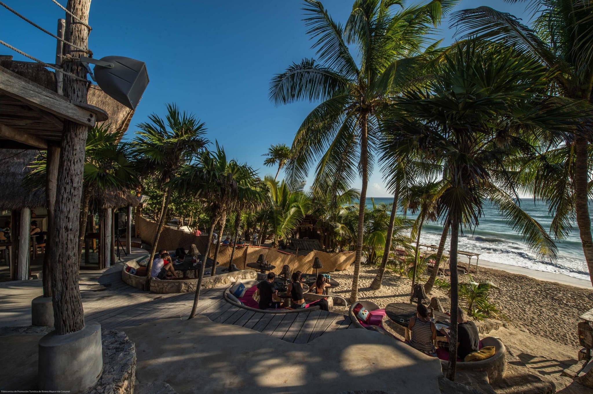 Club de playa entre palmeras en la costa de Tulum
