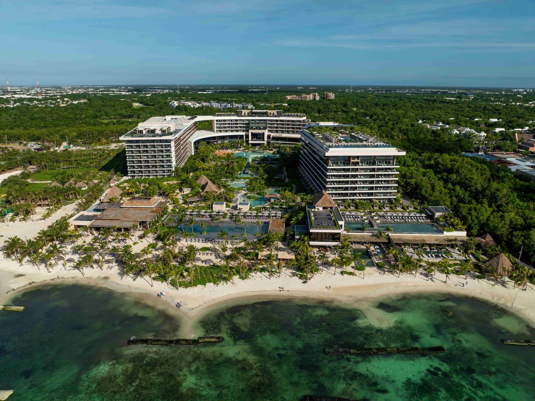 Vista aérea de un resort curvo entre la selva y la playa